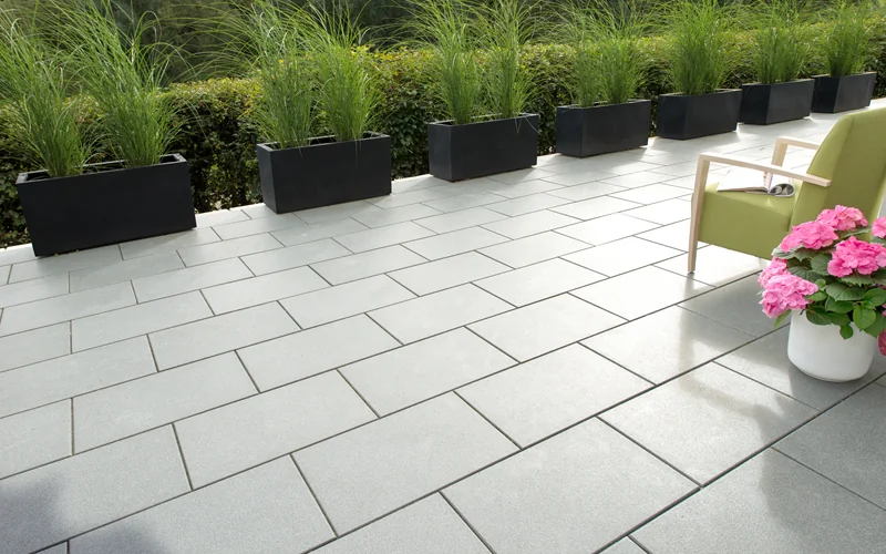 graue Terrassenplatten mit Pflanzenreihe am Rand