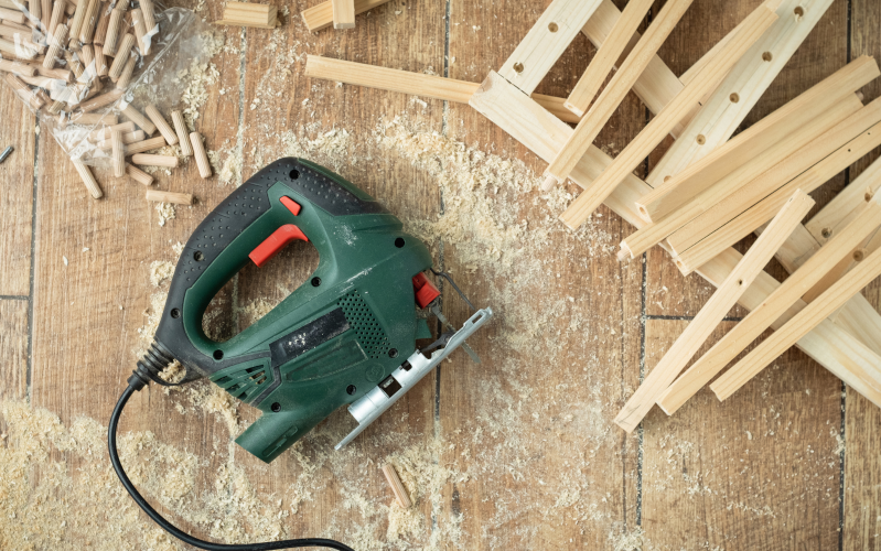 auf Holzboden liegen Holzteile, Späne und eine Stichsäge