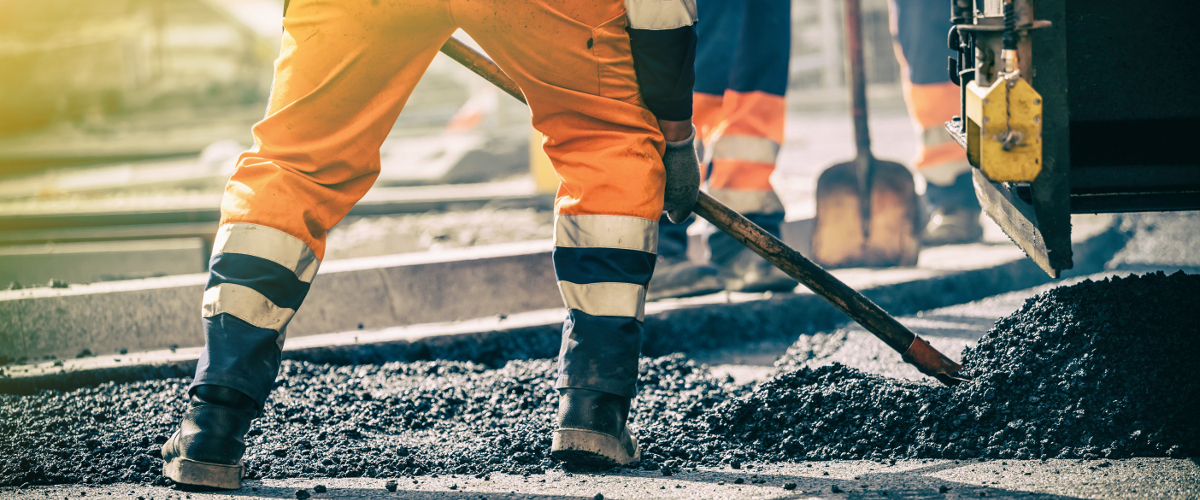 Arbeiter legen Asphalt auf Baustelle.