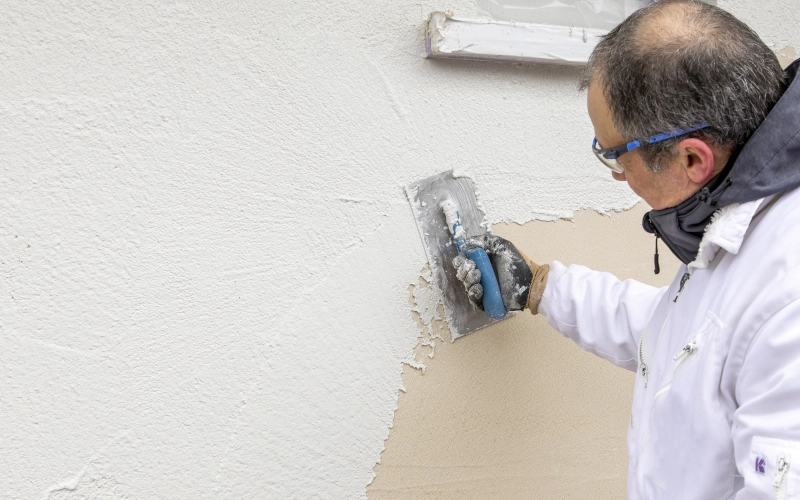 Handwerker bringt Spachtelmasse auf Hauswand auf
