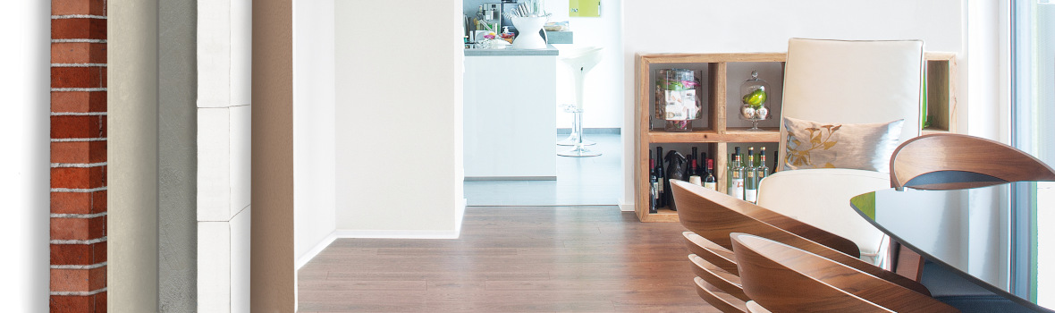 Helles Wohnzimmer mit Blick in eine Küche und einer Darstellung verschiedener Wandaufbauten links im Bild.