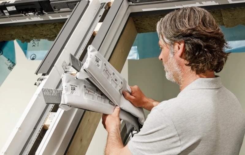 Handwerker baut Velux Zubehör in Dachfenster ein