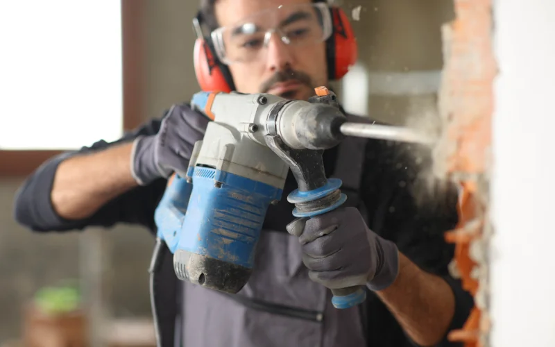 Handwerker arbeitet an einer Wand mit einem Bohrhammer