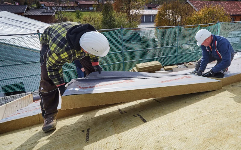 zwei Arbeiter decken Dach mit Dämmplatten ein