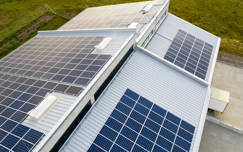 ein Firmengebäude von oben mit Metalldach und Solaranlagen darauf