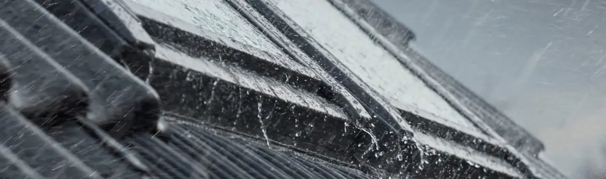 Regen tropft auf dunkles Dachfenster