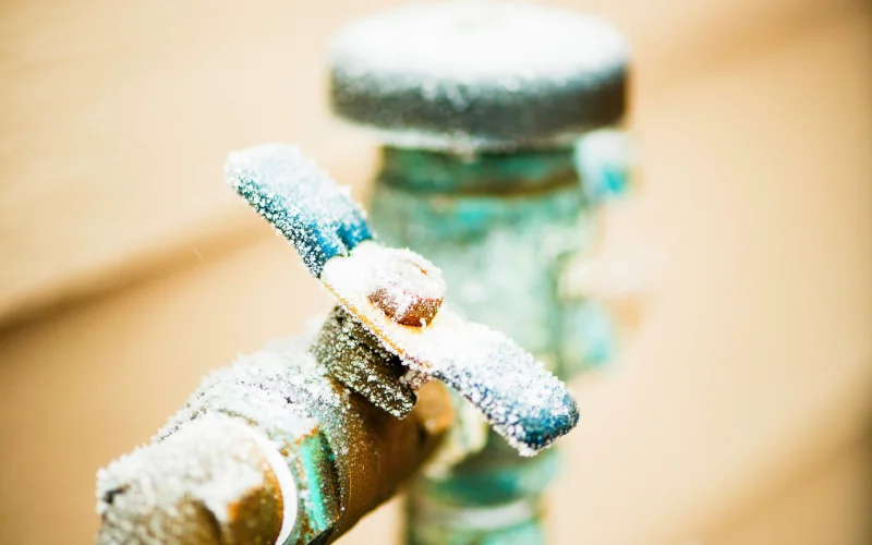 Garten Wasserhahn mit Schlauchanschluss überdeckt von Frost.