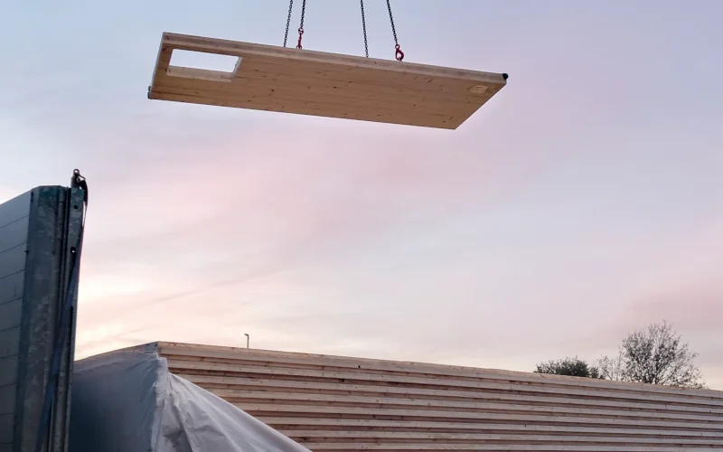 Bauteile werden mit einem Kran in der Dämmerung verladen
