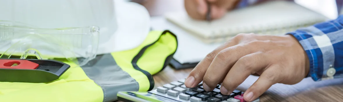 Handwerker sitzt am Schreibtisch und notiert etwas und rechnet mit dem Taschenrechner