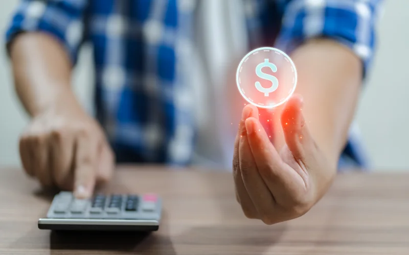 menschliche Hände halten ein Symbol für Geld und tippen am Taschenrechner
