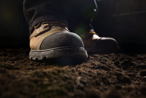 Handwerker mit Sicherheitsschuhen auf Erde 