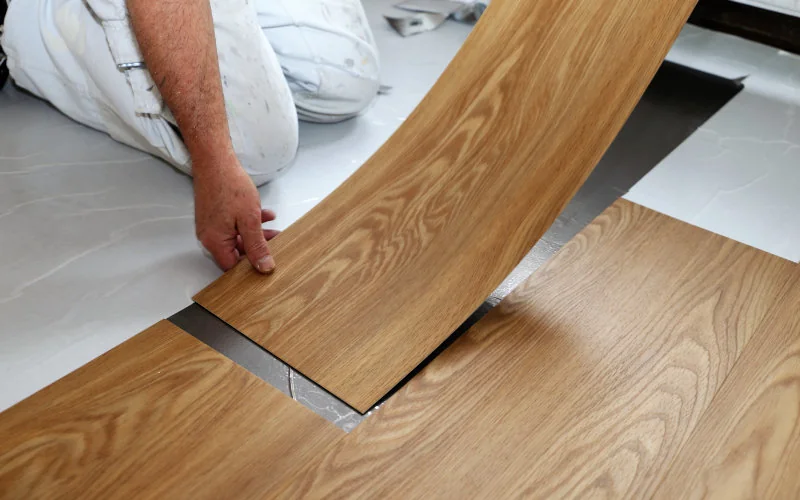 Mann verlegt Vinyl auf dem Klebeuntergrund auf dem Boden 