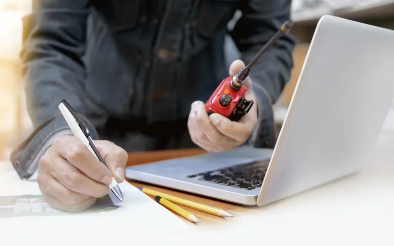 Handwerker mit Walky Talky und Laptop der etwas aufschreibt