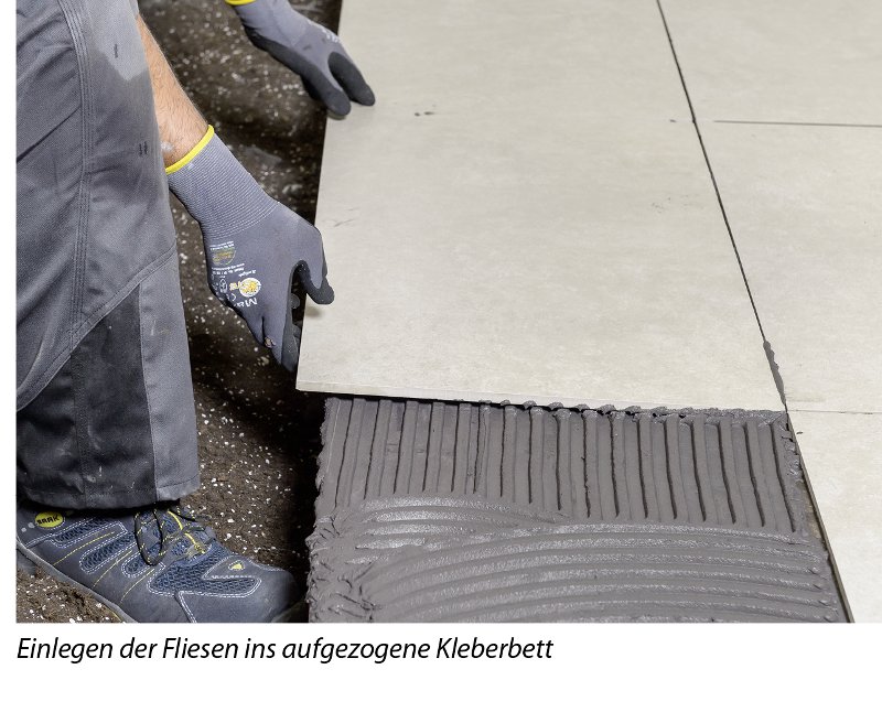 Mann verlegt Fliesen auf Kleberbett