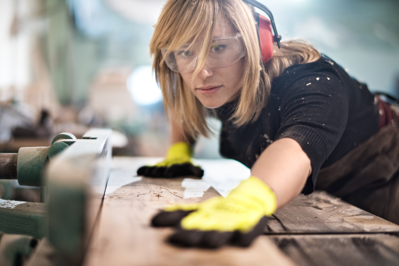 Tischlerin bearbeitet Holz in einer Werkstatt