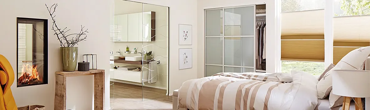 Wohnraum mit Glasschiebetüren vor dem Kleiderschrank und zum Badezimmer führend