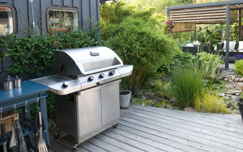 Gasgrill auf einer Terrasse mit Garten im Hintergrund 