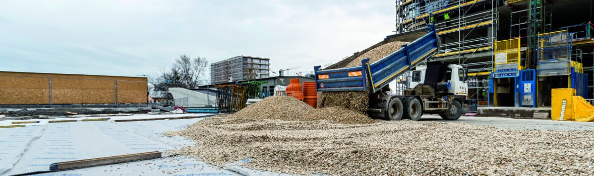 Auf der Baustelle wird Baumaterial vom Kipper gelassen