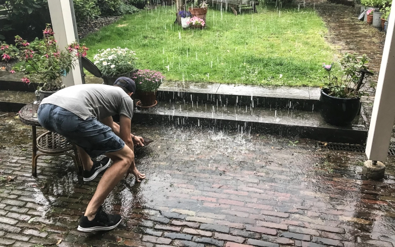 Mann prüft Wasserstand auf Terrasse beim Starkregen