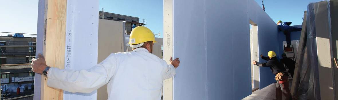 Handwerker bauen Fertigbauteile eines Hauses zusammen 