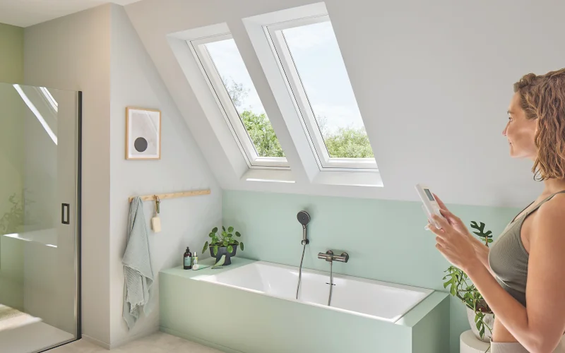 Rechts steht eine Frau im Badezimmer mit Dachfenstern