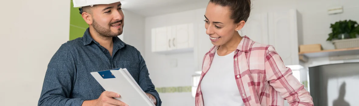 Handwerker und Auftraggeberin schauen sich gemeinsam den Auftrag an