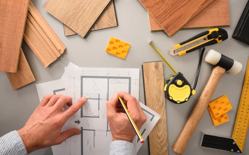 Hände die Renovierungsplan schreiben mit Holzmustern drumherum 