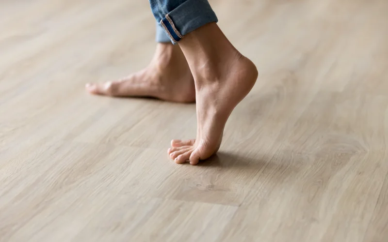 Mensch ohne Socken geht über einen Parkettboden