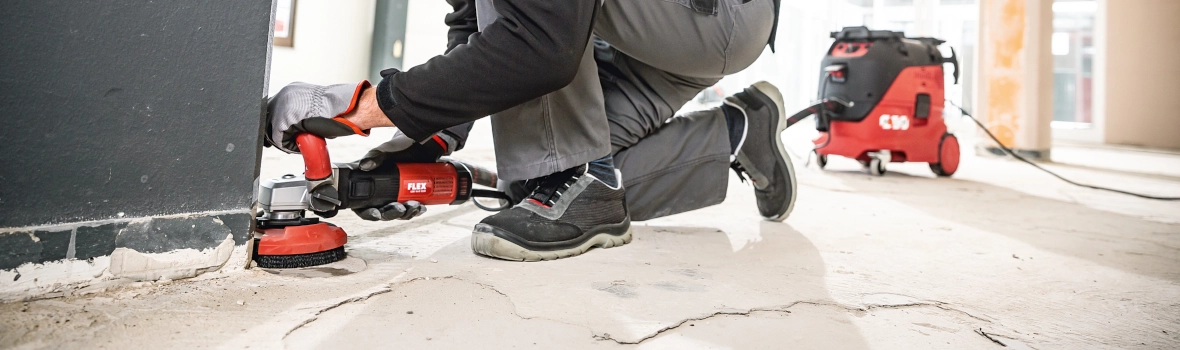Handwerker schleift den Betonboden mit dem LDE 16-8 125R Sanierungsschleifer der Firma FLEX