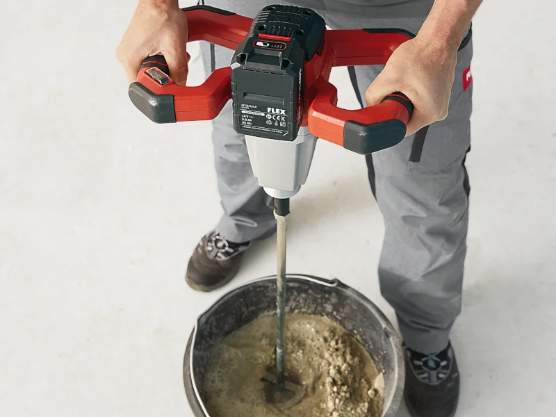 Handwerker mit Akku-Rührwerk in der Hand der Mörtel im Eimer rührt