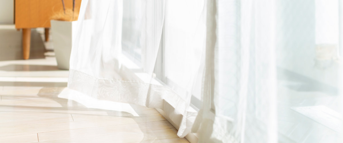 Bodenaufnahme von Vorhängen vor dem Fenster leicht in Bewegung durch Wind