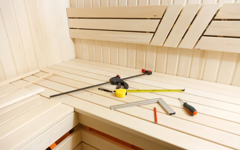 eine Holzsaune von Innen mit Handwerkzeug auf der Sitzfläche