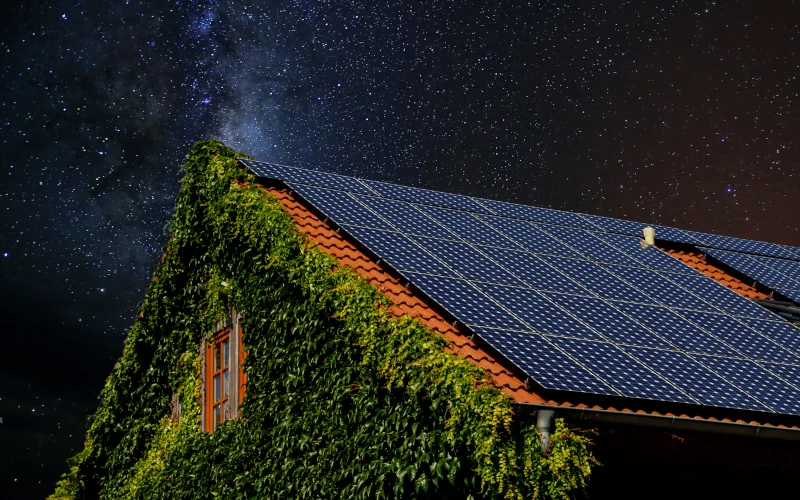Ein mit Solarzellen bedecktes Dach unter klarem Sternenhimmel, zeigt nachhaltiges Wohnen in der Natur.