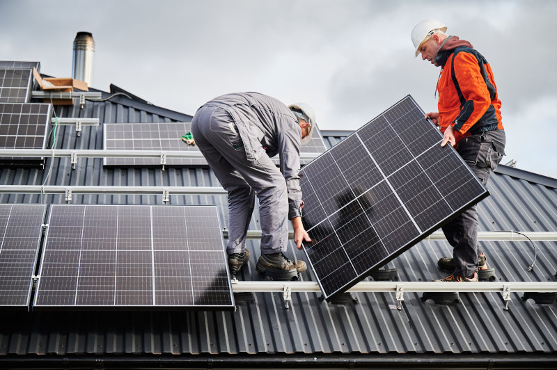 Arbeiter installieren Solarpanels auf einem Dach.