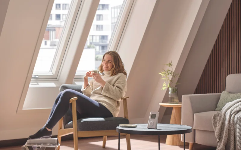 Frau sitzt auf Stuhl und Dachfenster im Hintergrund