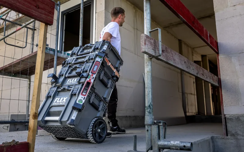 Handwerker zieht einen Aufbautrolley für Werkzeug und Baubedarf hinter sich her