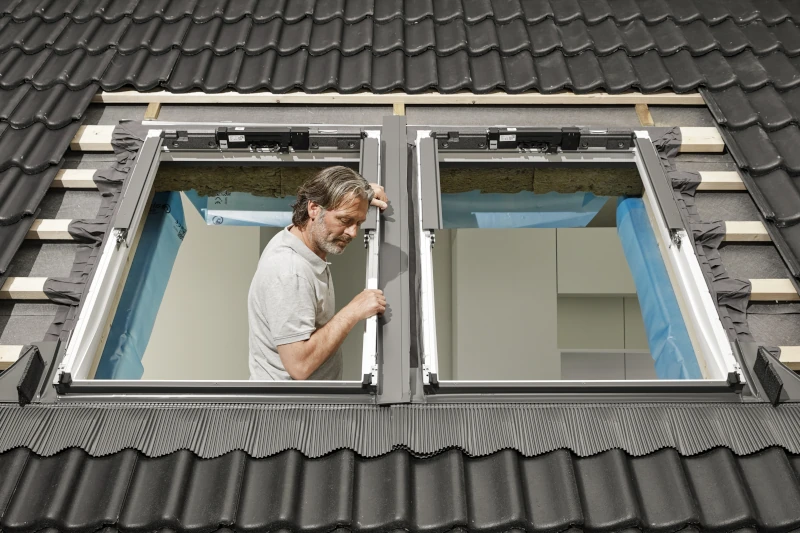 Handwerker baut Velux Zubehör in Dachfenster ein