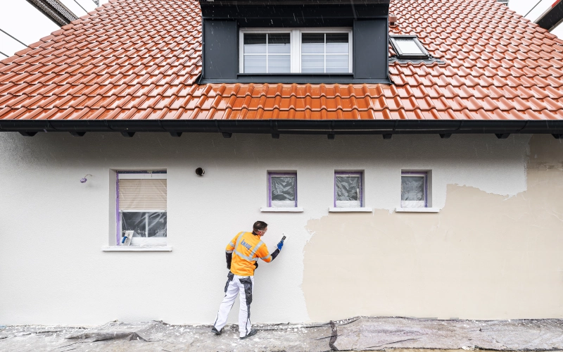 Handwerker bringt Spachtelmasse an Hauswand auf