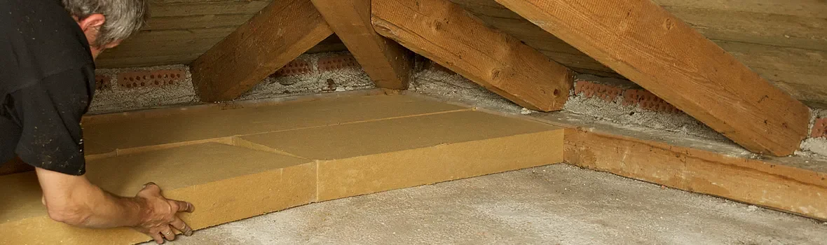 Mann verlegt Dämmplatten auf einem Dachboden