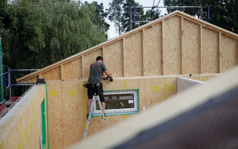 Handwerker steht an einem Haus mit Holzrahmenbauweise im Bau
