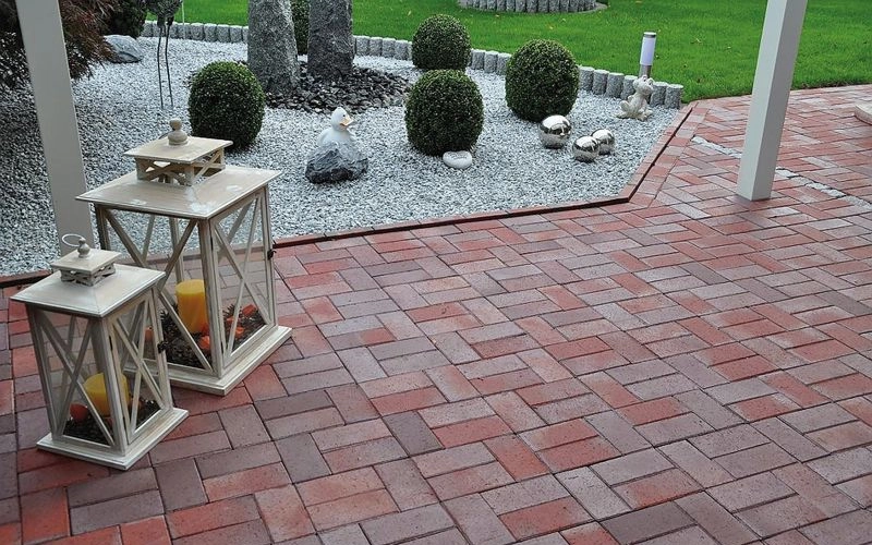 Terrasse mit Pflasterklinker und einem Kiesbeet sowie angrenzend einer Rasenfläche