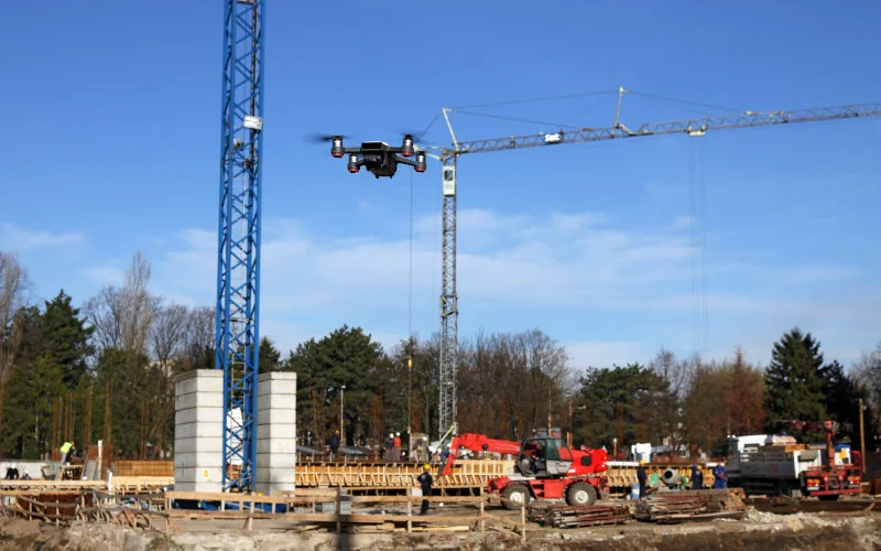 Drohne fliegt über eine Baustelle mit Kränen und Baustellenfahrzeugen 
