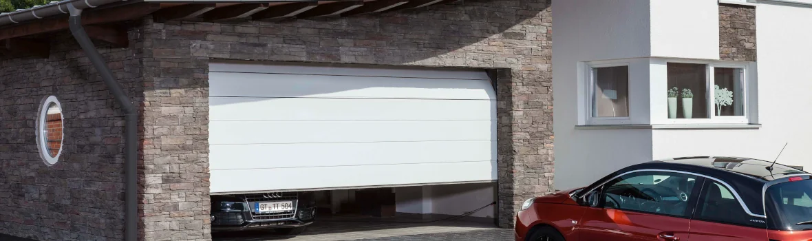 Wohnhaus mit Garage mit weißem Tor und Auto darin und davor