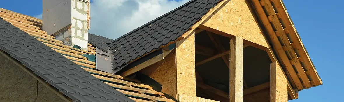 Unfertiges Hausdach mit OSB-Wänden und montierten Metall-Dachziegeln