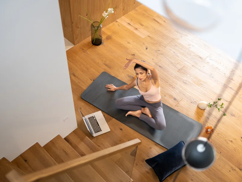 Frau sitzt auf einer Yogamatte auf dem Boden und macht Yoga