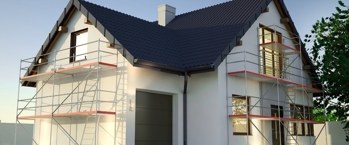 Ein Haus mit weißer Fassade ist von einem Gerüst umgeben