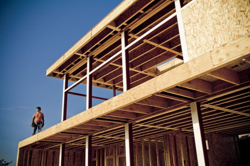 Mann steht im ersten Stock auf einem Holzhaus im Bau 