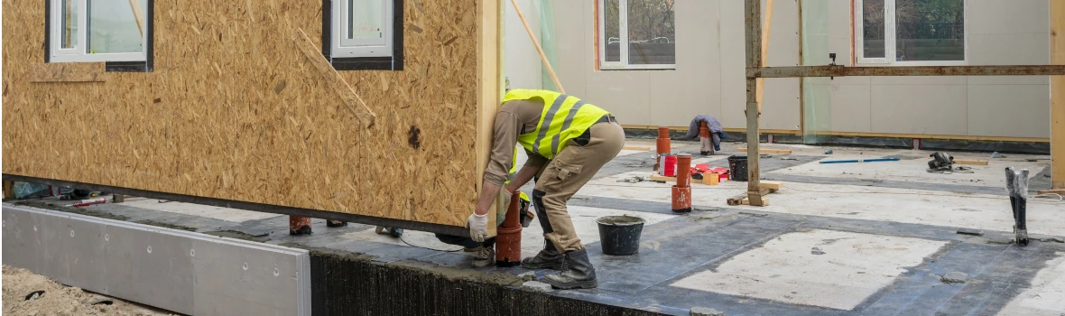 Arbeiter setzen Hauswand auf Fundament