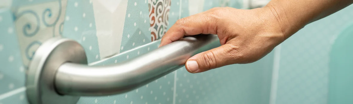 Frau hält sich an einem Haltegriff in einer Dusche fest