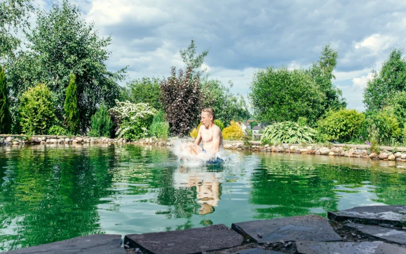 Kind springt in einem Schwimmteich im Garten 